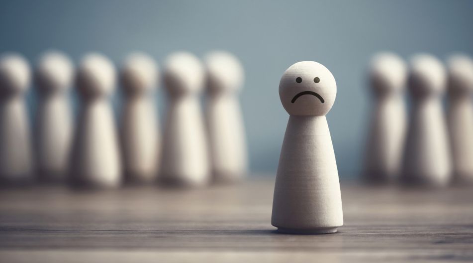 Das Bild zeigt eine einzelne Spielfigur mit einem traurigen Gesichtsausdruck im Vordergrund, während im Hintergrund mehrere Figuren in einer Gruppe stehen, die abgewandt scheinen. Es symbolisiert Isolation oder Ausgrenzung. Das Bild zeigt eine einzelne Spielfigur mit einem traurigen Gesichtsausdruck im Vordergrund, während im Hintergrund mehrere Figuren in einer Gruppe stehen, die abgewandt scheinen. Es symbolisiert Isolation oder Ausgrenzung.