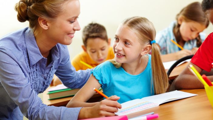 Eine Lehrerin hilft einer Schülerin bei ihren Aufgaben.